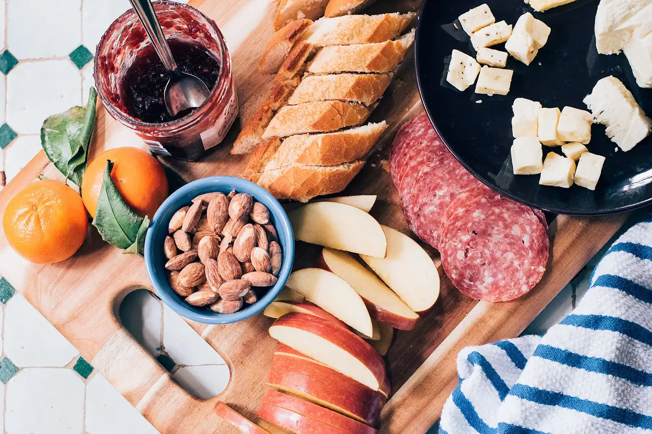 Tabla con pan, queso, salchichón, almendras y fruta